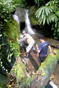 Karyawan PDAM Tomohon berupaya memperbaiki pipa yang rusak dihantam longsor dan pohon tumbang.